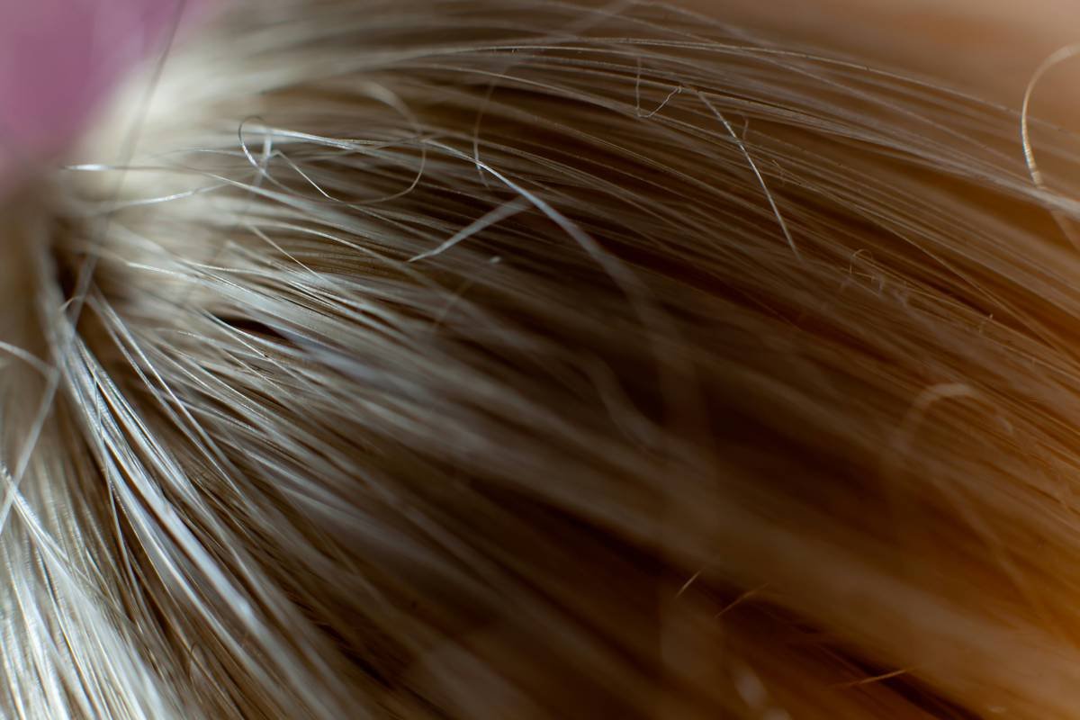 Stylist applying balayage hair sleek technique with micro-weaving on client with straight hair