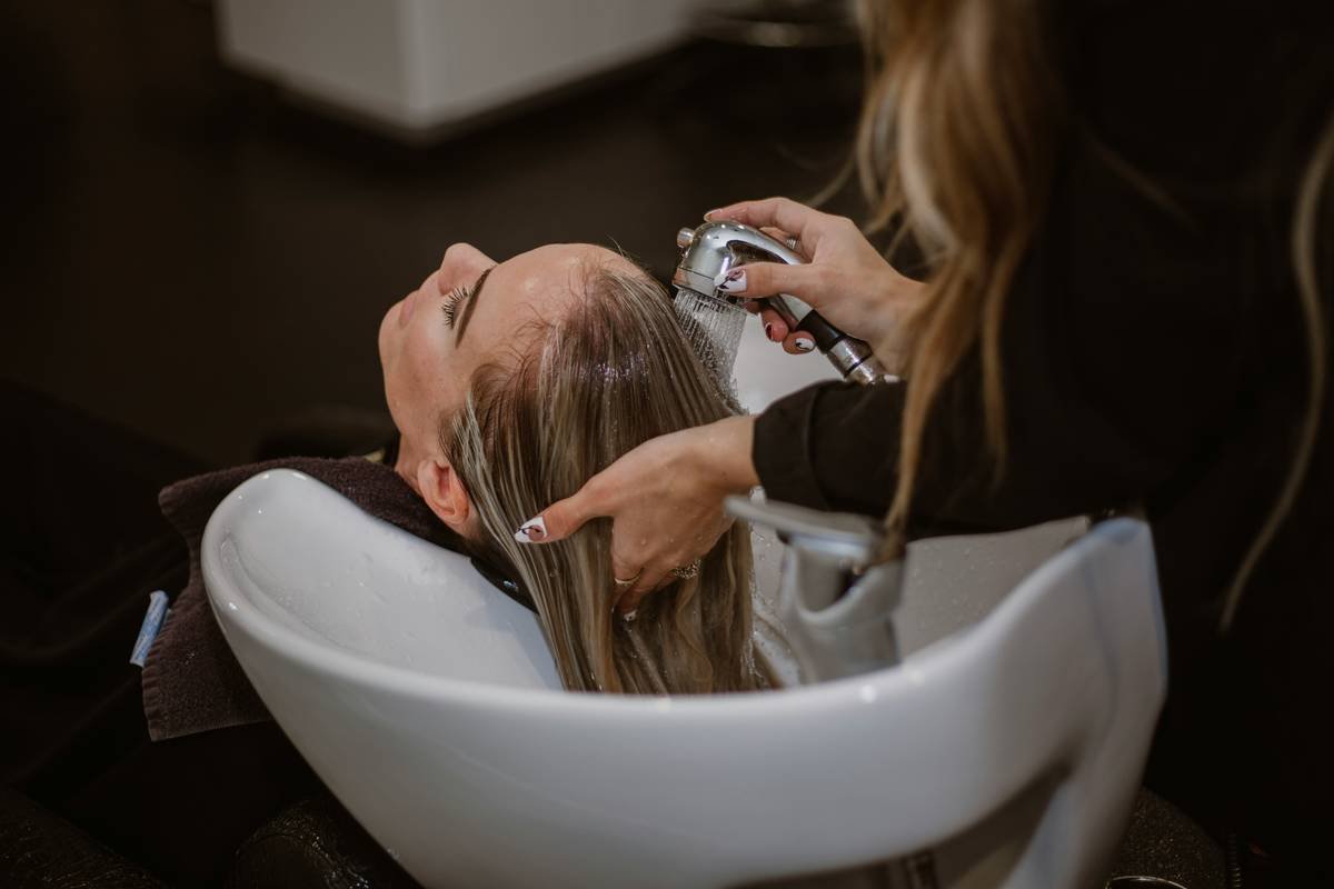 Close-up of skilled colorist applying hand-painted highlights during a balayage salon experience
